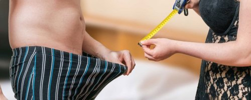 Eine Frau misst die Länge eines Mannes eines Mitglieds